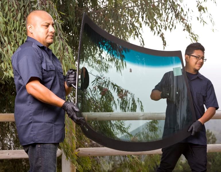 Two men in Miami are lifting a glass window, highlighting their teamwork in a construction project